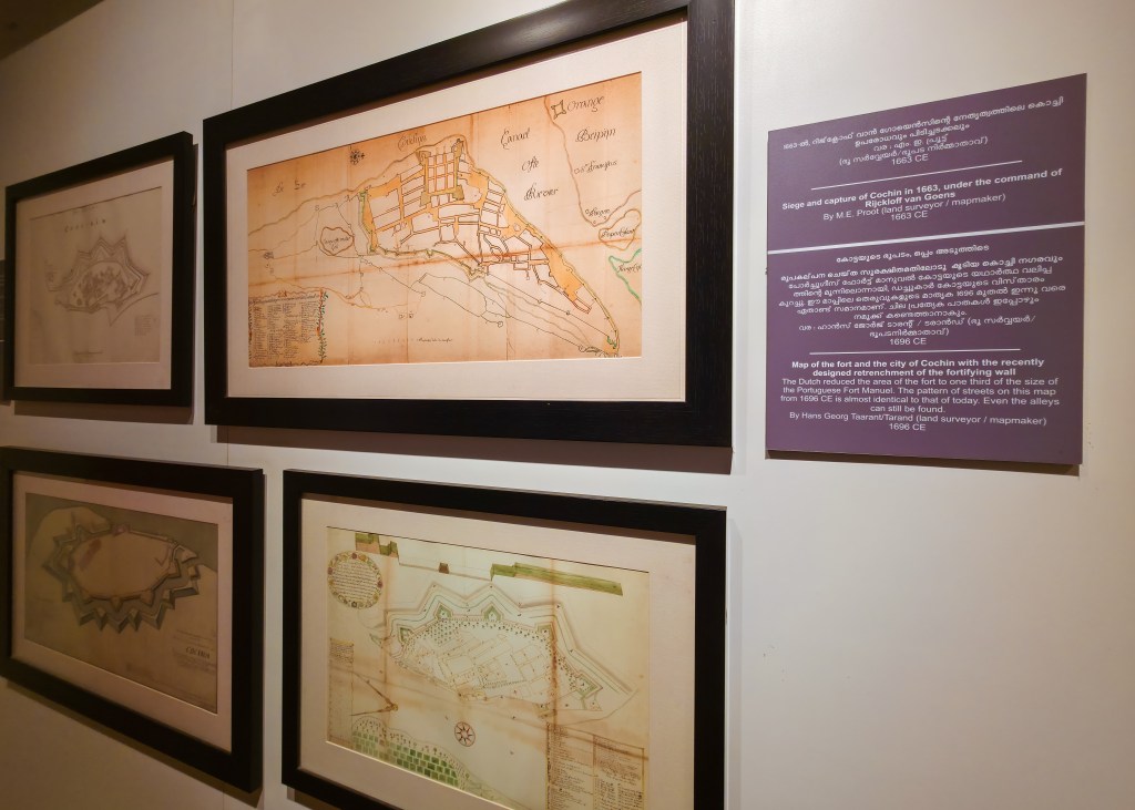 Two framed historical illustrations of Kochi hang on a gallery wall alongside an explanation of the images. 